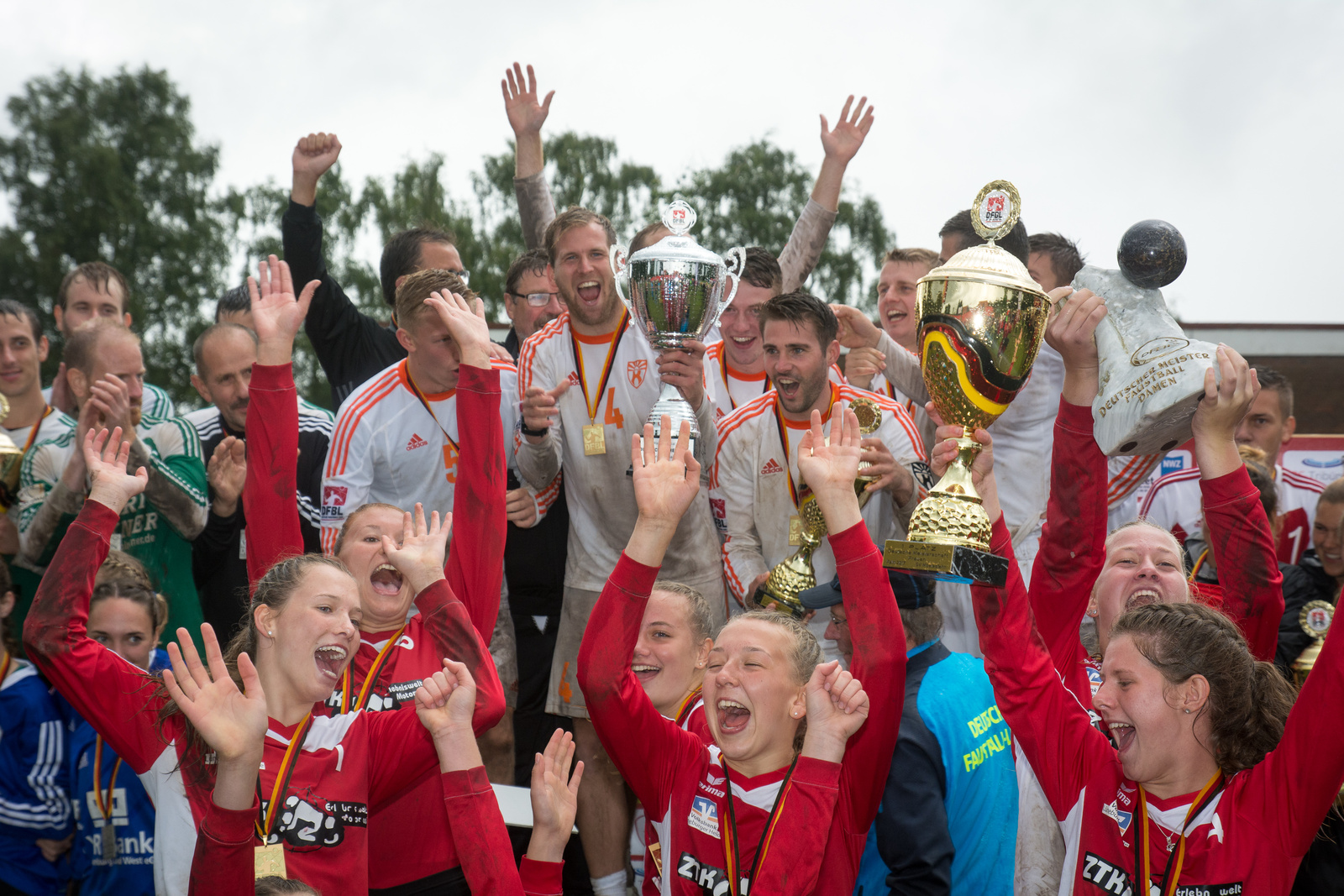 Jubelnde Faustballerinnen und Faustballer mit Pokalen bei der Siegerehrung der DM 2017 in Moslesfehn.